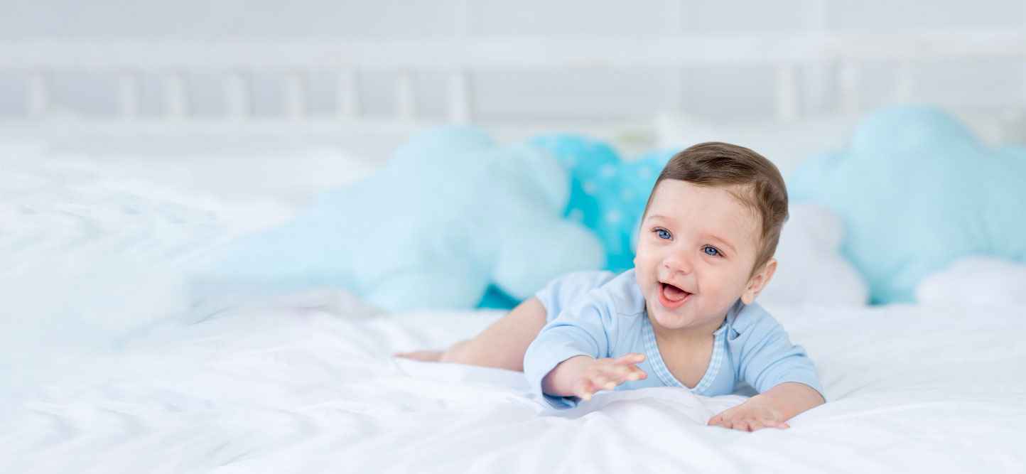 Baby lying on a bed with blue pillows